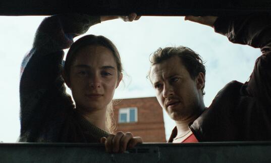 A girl and a man look into a boot of a car.